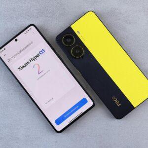 Top view of two smartphones displaying Xiaomi HyperOS update screen and POCO branding on a plain surface.